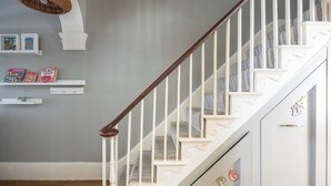 A staircase with white railings and a wooden handrail, leading to a landing with a white wall and a shelf with books. - Charming Georgian Retreat | Walk to Beach & City - Pass the Keys (Brighton)