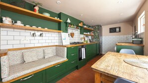 A kitchen with green cabinetry, a wooden bench, and a tiled backsplash. - Charming Georgian Retreat | Walk to Beach & City - Pass the Keys (Brighton)