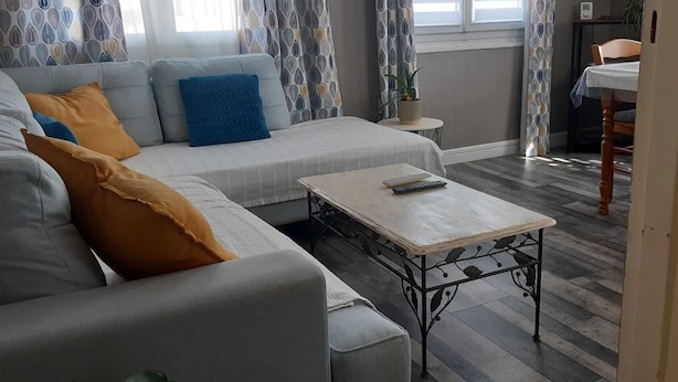 Uma sala de estar com sofá, mesa de centro e um espaço de jantar com uma cadeira e mesa.