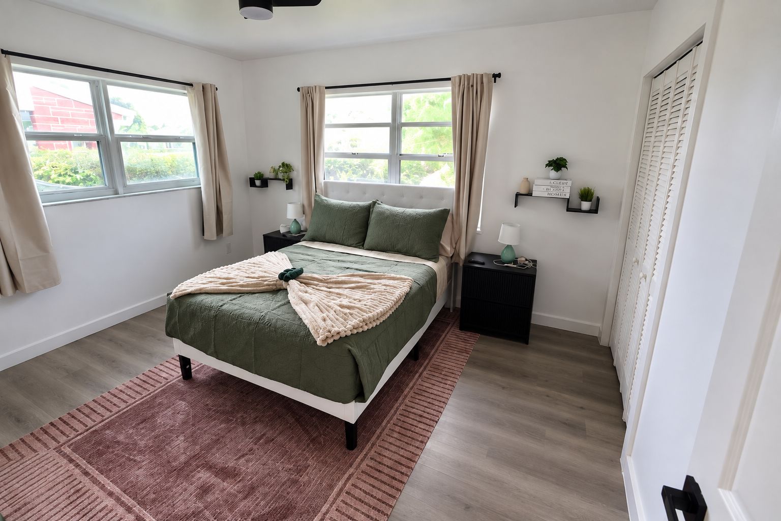 Ein Schlafzimmer mit Bett, Nachttischen, einem Fenster und einer Tür.