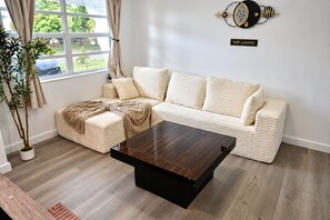 Un salon moderne avec un canapé d’angle, une table basse et une plante en pot.