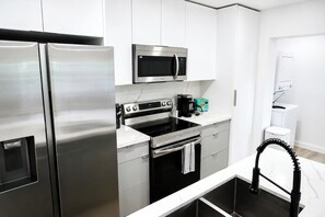 Una cocina moderna con electrodomésticos de acero inoxidable, cafetera y un lavamanos pequeño.