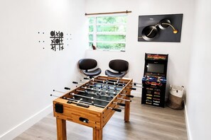 A room with a foosball table, two chairs, a window with a view, and a foosball machine. - Near Hard Rock . Game Room + 15 Min to Beach (Hollywood)