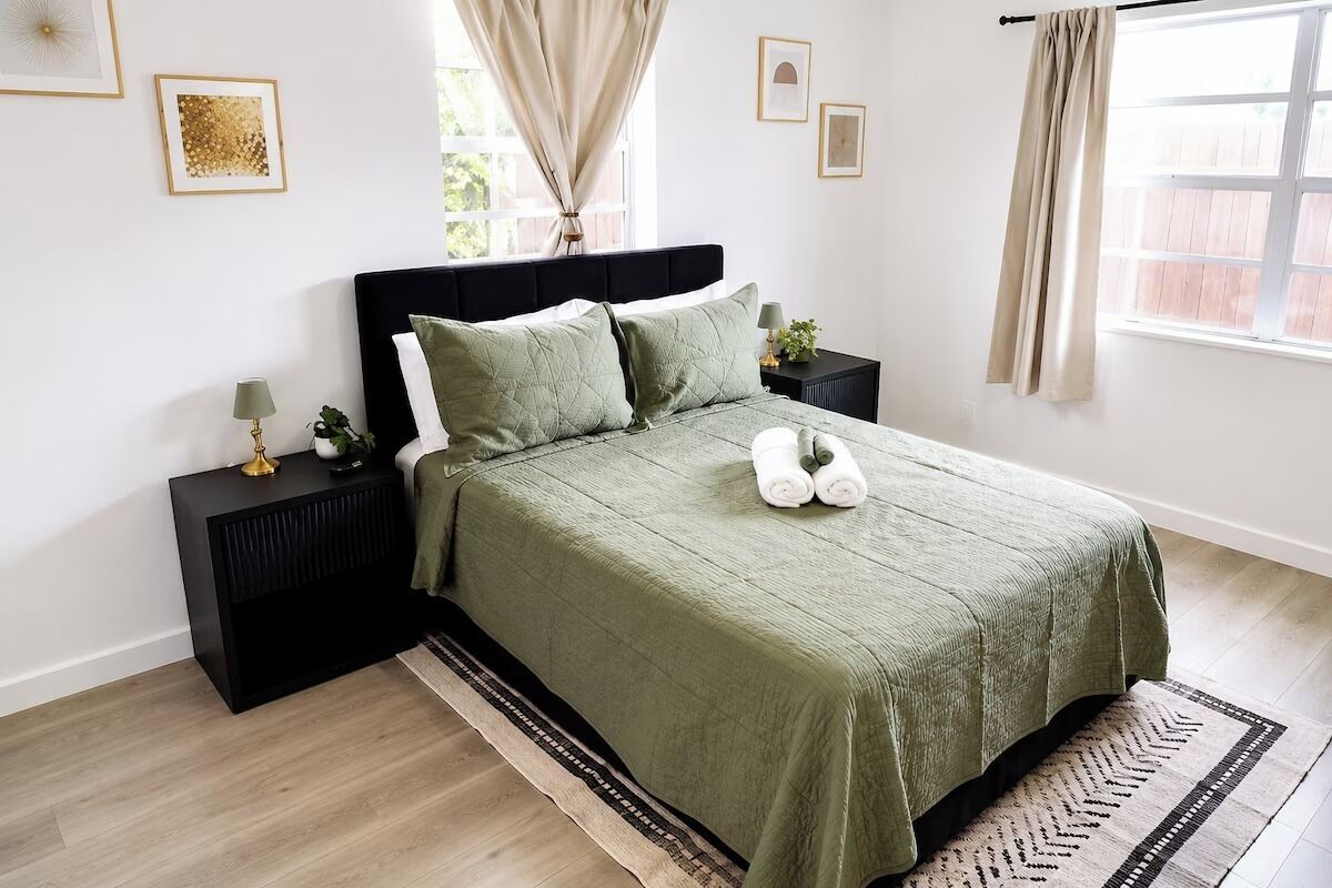 Ein Schlafzimmer mit einem Bett, Nachttischen, einem Fenster mit Vorhängen und einem Teppich.
