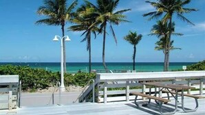 A beachside walkway with palm trees, a picnic table, and a view of the ocean. - Near Hard Rock . Game Room + 15 Min to Beach (Hollywood)