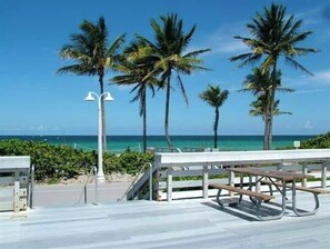 A beachside walkway with palm trees, a picnic table, and a view of the ocean. - Near Hard Rock . Game Room + 15 Min to Beach (Hollywood)