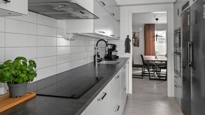 Eine moderne Küche mit weißen Schränken, einer schwarzen Arbeitsplatte und einem Edelstahl-Kühlschrank.