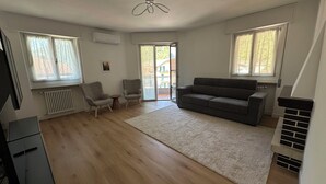 Een woonkamer met een bank, twee fauteuils, een tafeltje en een open haard.