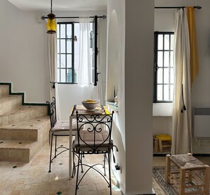 Ein Zimmer mit Esstisch, Stühlen, einer Treppe und einem fenster mit Vorhängen.