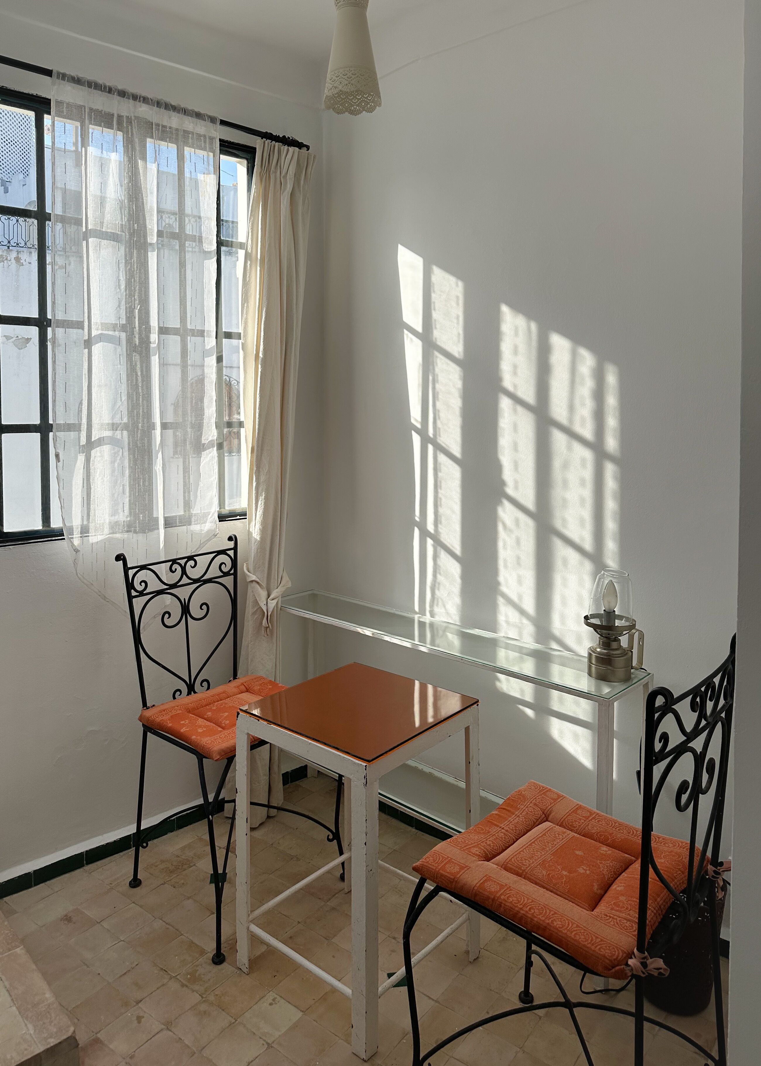 A room with a table and two chairs, a radiator, and a window with curtains.