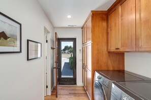 A laundry room with wooden cabinets, a washing machine, and a door leading outside.
