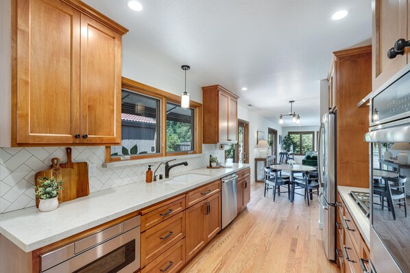 A modern kitchen with wooden cabinets, a stainless steel refrigerator, and a dining area with a table and chairs.