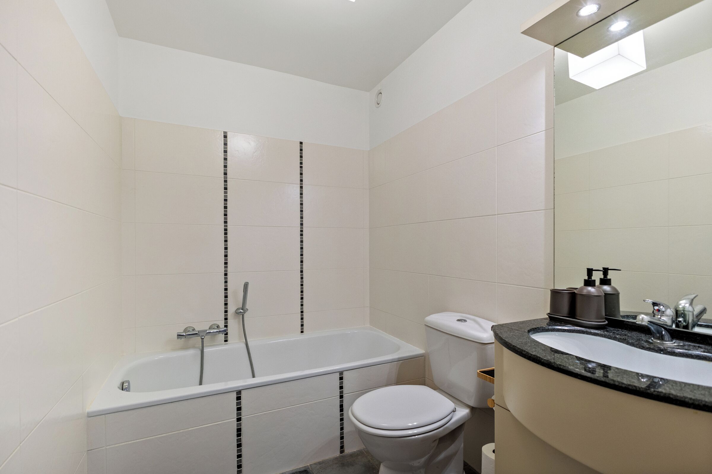 Un bagno moderno con vasca, water e lavabo con specchio.