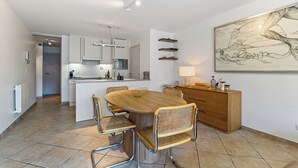 Eine moderne Küche mit weißen Schränken, einer zentralen Kochinsel und einem Essbereich mit Holztisch und Korbstühlen.