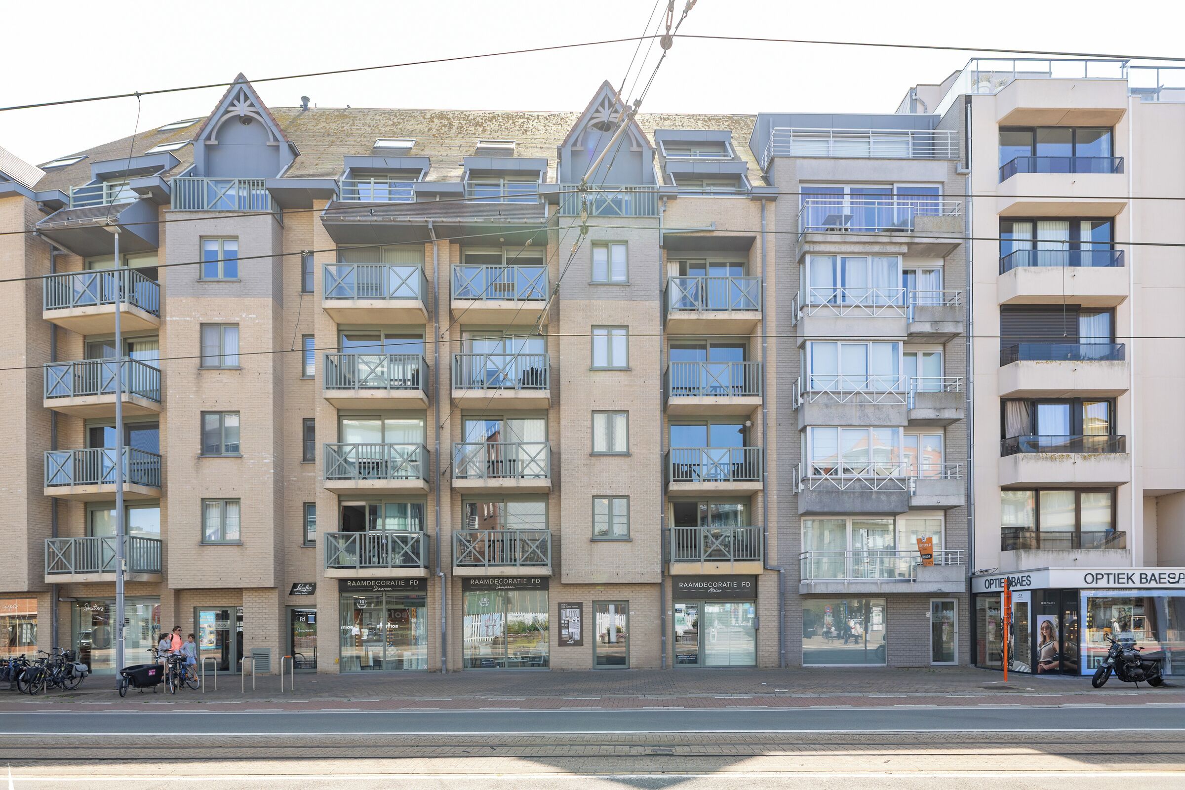 A multi-story residential building with balconies, a ground-floor shop, and a visible storefront.