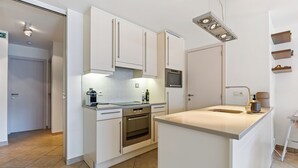 Eine moderne Küche mit weißen Schränken, einem eingebauten Backofen und einer Kochinsel.
