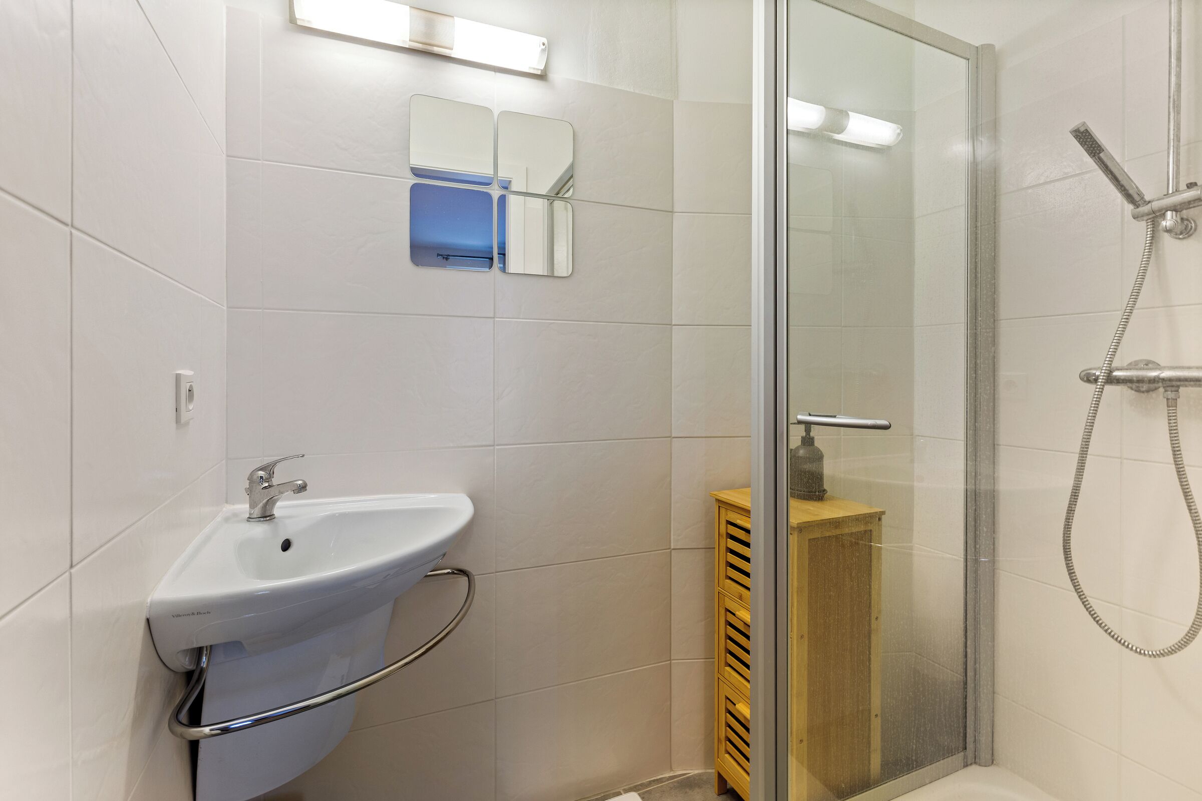 Une salle de bain moderne avec une douche à parois de verre, un lavabo blanc et un miroir.