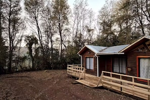 Dos cabañas de madera con techos de metal, rodeadas de árboles.