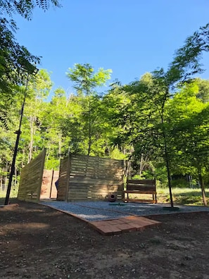 Un jardín cercado con un banco de madera y una pequeña construcción de madera.