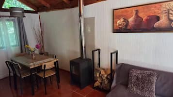 A cozy living area with a fireplace, a dining table with chairs, and a sofa with a throw pillow.