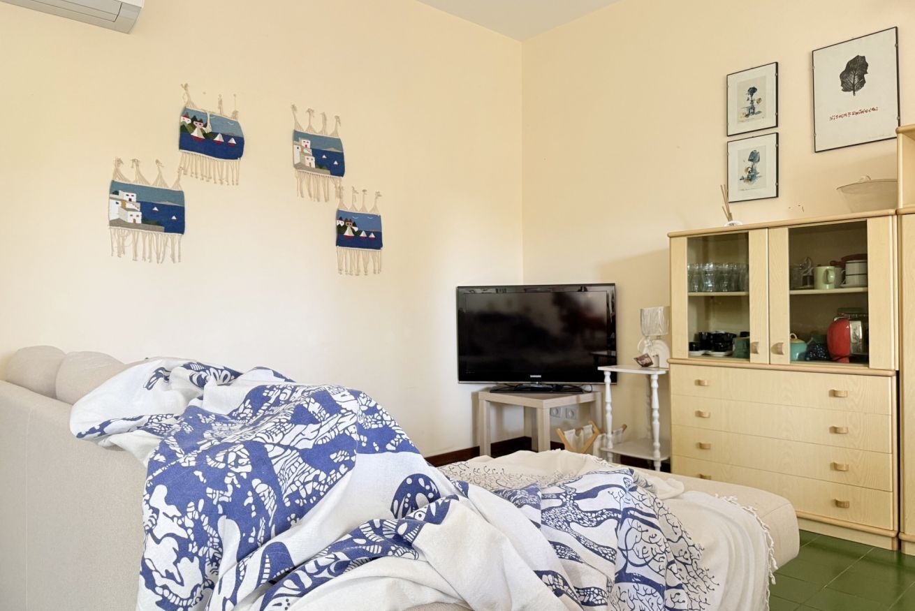 Un dormitorio con cama, televisión, aparador y decoración en la pared.