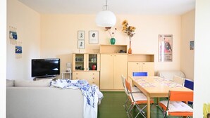 Una sala de estar con sofá, televisión y comedor con mesa y sillas.