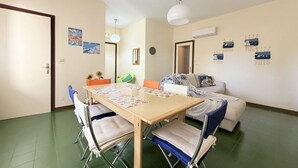 Una habitación con una mesa de madera, sillas, un sofá y una lámpara en el techo.
