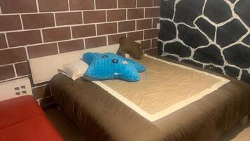 A bedroom with a brick-patterned headboard, a bed with a brown bedspread, a blue plush toy, and a red chair.
