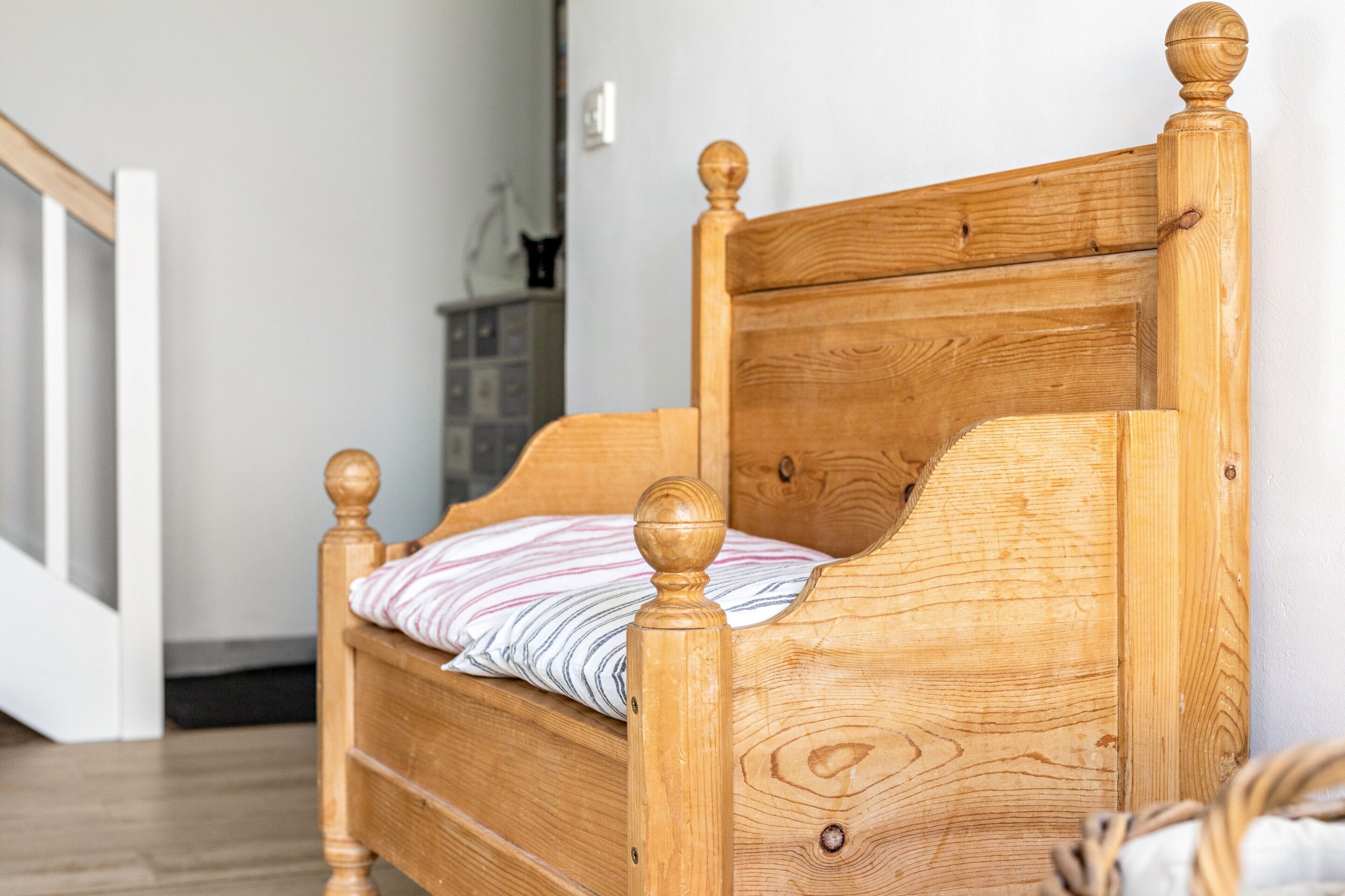A wooden bed with a headboard and footboard, a striped pillow, and a wooden floor.