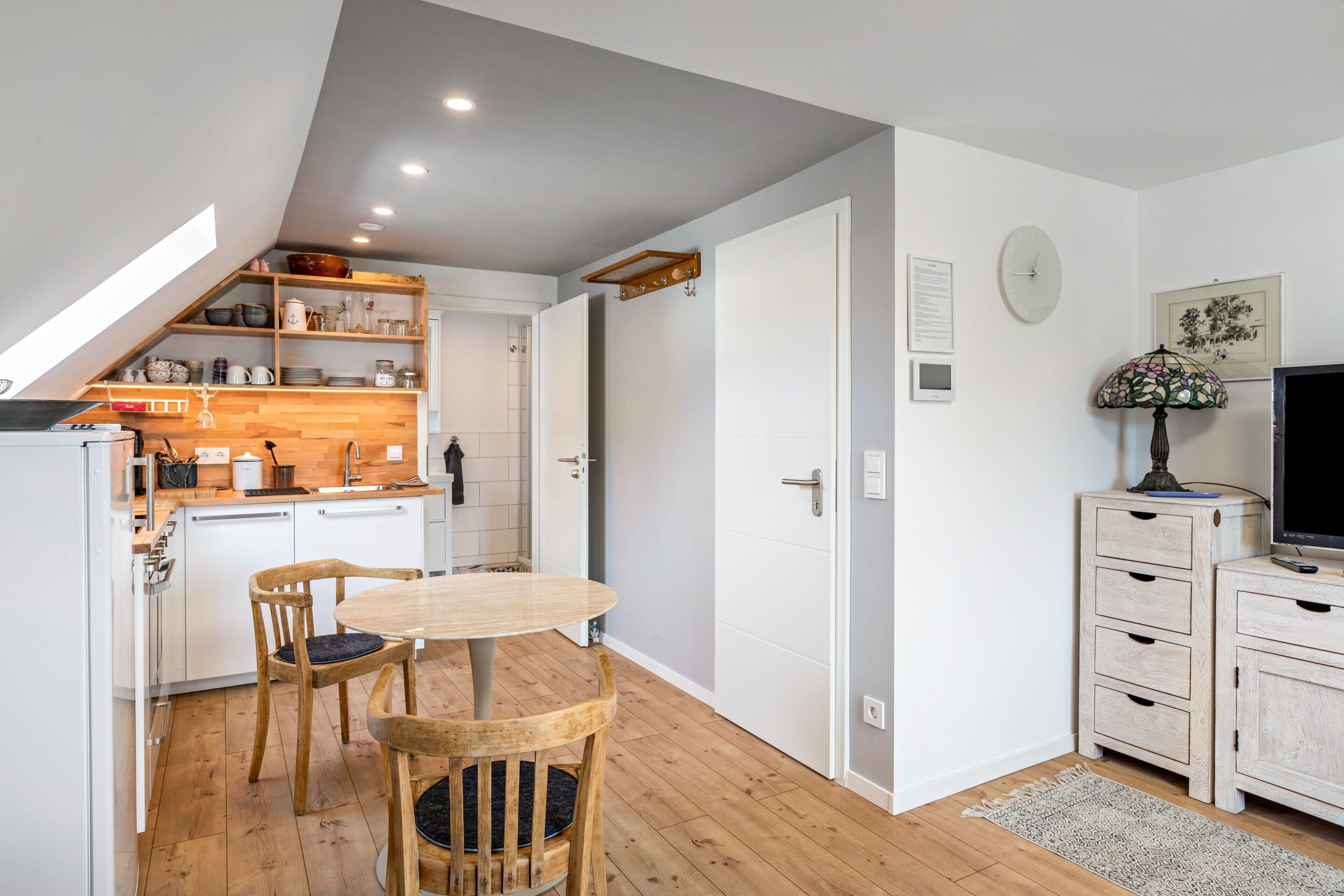 A compact kitchen with a dining area, wooden cabinets, and a small TV.