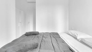 A minimalist bedroom with a bed, pillows, and an air conditioning unit. - CRE9 [Loreto - Cathedral] • Central • Modern • (Milano)