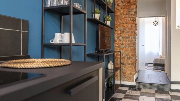 Une cuisine moderne avec des meubles de couleur noire, un set de table en fibres tressées et un mur en briques.