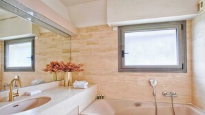 Un baño con una bañera grande, un lavabo doble, un espejo y una ventana.