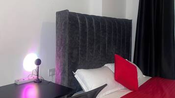 Une chambre d’hôtel comprenant un lit, un bureau, une chaise, une table de chevet et un tableau accroché au mur.