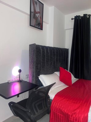 Ein Hotelzimmer mit Bett, Schreibtisch, Stuhl, Nachttisch und einem an der Wand hängenden Bild.