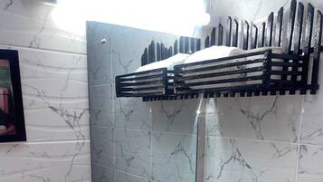 Une salle de bain avec un lavabo blanc, un miroir et un porte-serviettes noir.