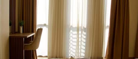 A hotel room with a bed, a desk, and a chair.