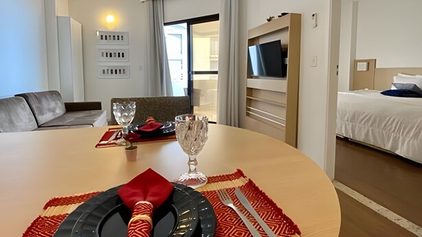 Una habitación de hotel con zona de comedor, cama y televisión.