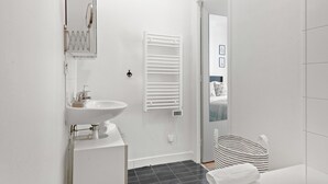 Ein modernes Badezimmer mit einem weißen Waschbecken, einem Handtuchhalter und einer Duschkabine.