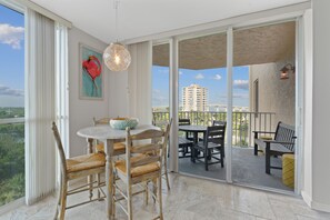 Ein Balkon mit Tisch und Stühlen, Blick auf die Stadt und ein Bild an der Wand.
