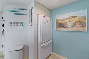 Eine Küche mit einem weißen Kühlschrank, einer weißen Toilette und einem Bild von einem Boot am Strand.