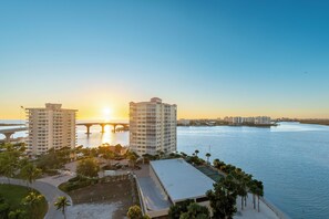 Ein Hotel am Wasser mit Blick auf Sonnenuntergang, eine Brücke und einen Strand.