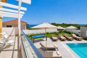 Un espace aménagé au bord de la piscine, avec des chaises longues, une table de billard et des parasols.