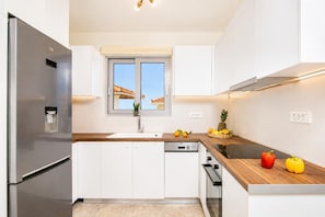 A modern kitchen with a stainless steel refrigerator, a window with a view, a wooden countertop, and a dishwasher. - Kaletzia Villa IV - Four Bedroom Villa, Sleeps 8 (Zakinthos)