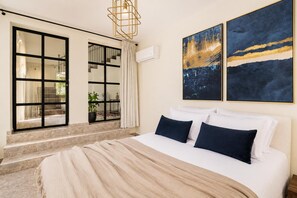A bedroom with a large bed, a window with a view of the outdoors, and two abstract paintings on the wall. - Kaletzia Villa IV - Four Bedroom Villa, Sleeps 8 (Zakinthos)