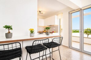 Una cucina moderna con un'area bar, tre sgabelli da bar neri e piante in vaso.