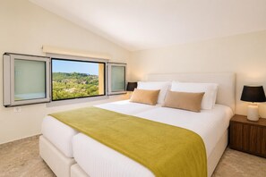 Una camera d'albergo con un letto grande, due comodini, una finestra con vista e una coperta verde.