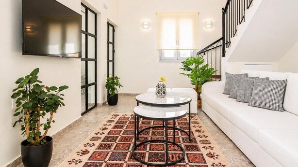 Una sala moderna con sofá, una mesita de centro y plantas en macetas.
