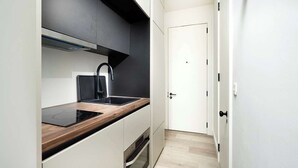 Een kleine keuken met een ingebouwde kookplaat, een spoelbak en een magnetron.