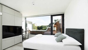 Een moderne slaapkamer met een groot bed, een televisie en een schuifdeur naar een buitenruimte.